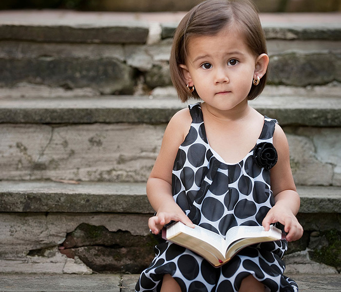 Photo image of little girl holding a Bible looking at the camera