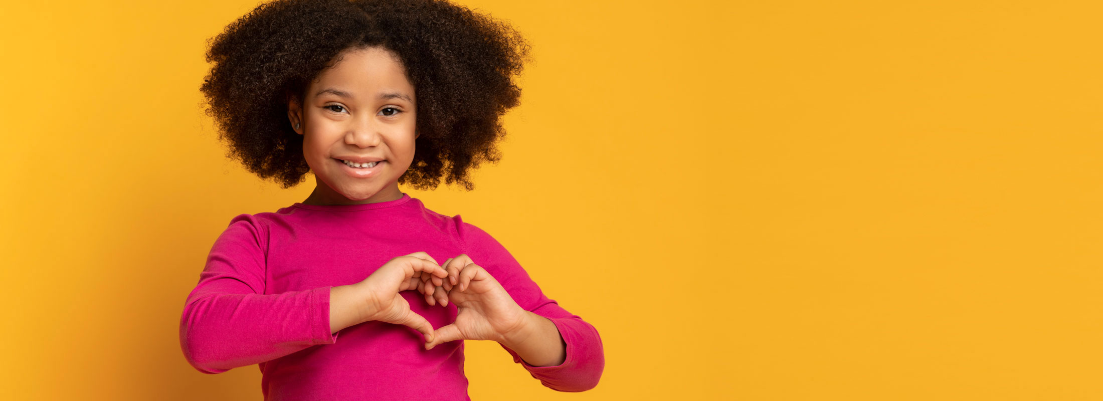 Sunday School Activities about love photo of young girl making a heart symbol.